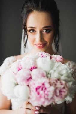 Gelin çiçekli büyük ve güzel bir düğün buketi tutuyor..