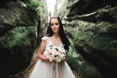 Lüks bir gelin, bir kız buketle poz veriyor ve gülümsüyor..