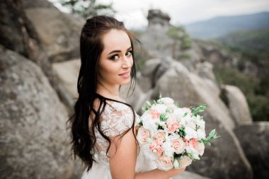 Gelin çiçekli büyük ve güzel bir düğün buketi tutuyor..