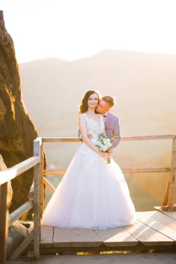 Doğadaki düğün çifti birbirine sarılıyor. Beyaz elbiseli güzel bir kız. Takım elbiseli adam.