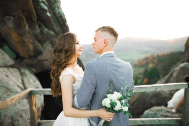 Dağların arka planında sevgi dolu bir koca ve kadın. Sevgili çift duygusal olarak vakit geçirir..