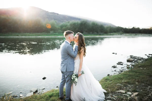 Piękna Para Ślubna Całująca Się Obejmująca Brzeg Górskiej Rzeki Kamieniami — Zdjęcie stockowe
