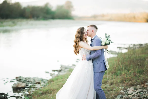 美しい結婚式のカップルのキスと石と山の川の岸の近くに抱擁 — ストック写真