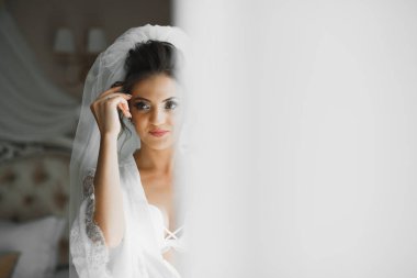 Cüppeli muhteşem gelin bir odada düğün töreni için poz veriyor ve hazırlanıyor..