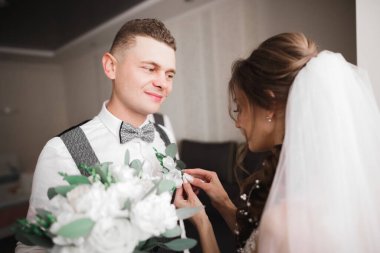 Gelin, damat ceketine yeşil yapraklı beyaz yaka çiçeğini iğneledi..