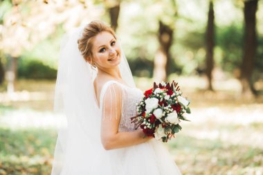 Gelin çiçekli büyük ve güzel bir düğün buketi tutuyor..