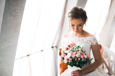 Lüks bir gelin, bir kız buketle poz veriyor ve gülümsüyor..