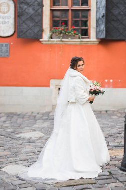 Çekici gelinin portresi, uzun saçlı, büyük buketli poz veren..