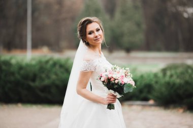 Çekici gelinin portresi, uzun saçlı, büyük buketli poz veren..