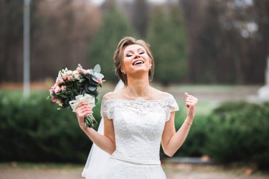 Lüks bir gelin, bir kız buketle poz veriyor ve gülümsüyor..