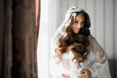 Cüppeli muhteşem gelin bir odada düğün töreni için poz veriyor ve hazırlanıyor..