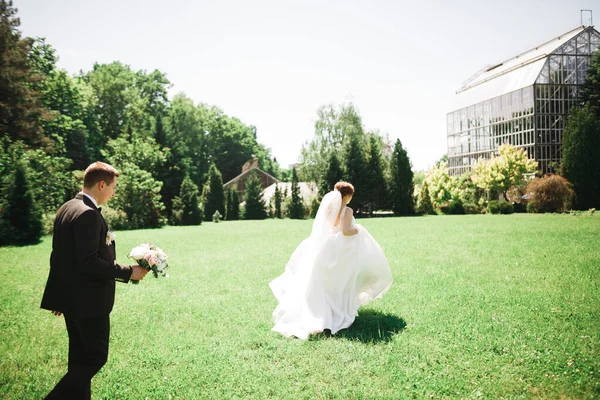 一对时髦的新婚夫妇 婚礼当天 新娘带着花束在公园里从新郎身边跑开 — 图库照片