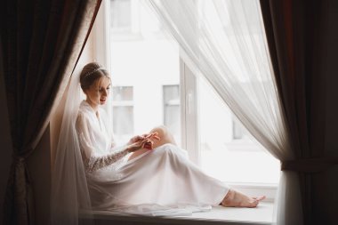 Cüppeli muhteşem gelin bir odada düğün töreni için poz veriyor ve hazırlanıyor..