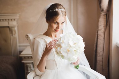 Lüks bir gelin, bir kız buketle poz veriyor ve gülümsüyor..