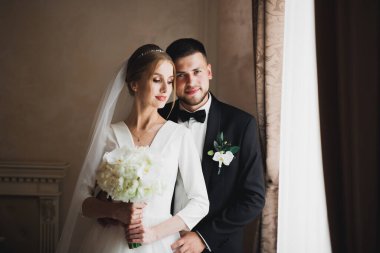 Güzel, genç bir çift ellerinde çiçeklerle poz veriyorlar..