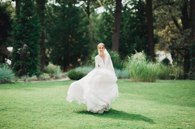 Parkta poz veren gelinlikli güzel, lüks bir gelin..