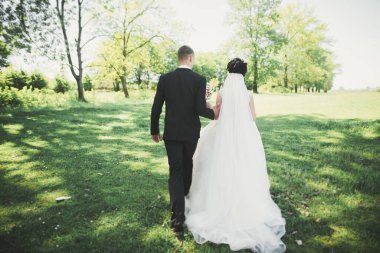 Yeni evli çift el ele tutuşurken parkta koşup zıplıyorlar..