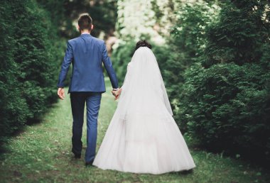 Yeni evli çift el ele tutuşurken parkta koşup zıplıyorlar..