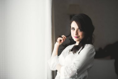 Cüppeli muhteşem gelin bir odada düğün töreni için poz veriyor ve hazırlanıyor..