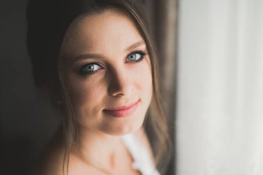 Cüppeli muhteşem gelin bir odada düğün töreni için poz veriyor ve hazırlanıyor..