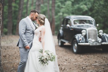 Güzel yeni evli çift siyah arabanın yanında poz veriyor..