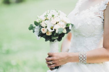 Gelin çiçekli büyük ve güzel bir düğün buketi tutuyor..