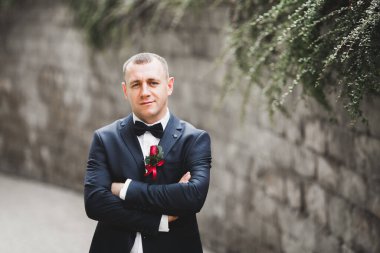 Yaka çiçeğiyle poz veren mutlu yakışıklı damat..