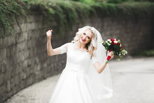 Portrait of stunning bride with long hair posing with great bouquet.