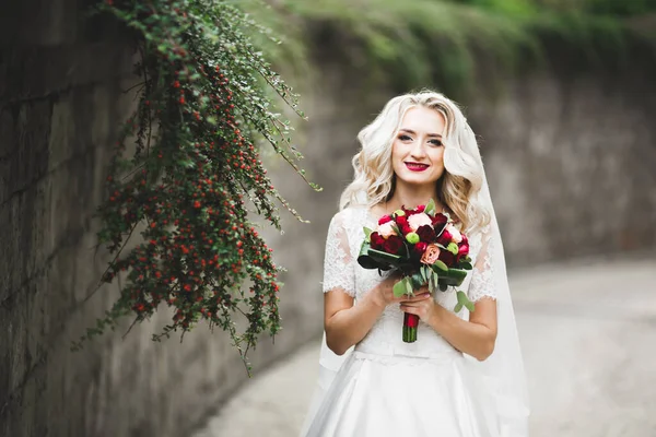 Portrait of stunning bride with long hair posing with great bouquet.