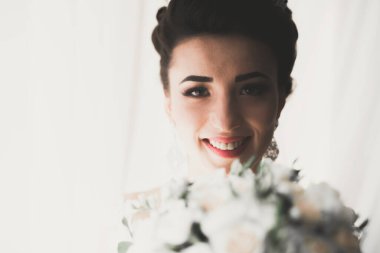 Cüppeli muhteşem gelin bir odada düğün töreni için poz veriyor ve hazırlanıyor..