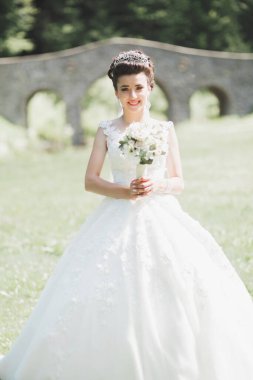 Çekici gelinin portresi, uzun saçlı, büyük buketli poz veren..