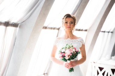 Lüks bir gelin, bir kız buketle poz veriyor ve gülümsüyor..