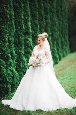 Çekici gelinin portresi, uzun saçlı, büyük buketli poz veren..
