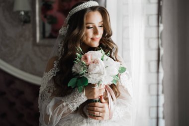 Lüks bir gelin, bir kız buketle poz veriyor ve gülümsüyor..