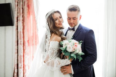 Güzel, genç bir çift ellerinde çiçeklerle poz veriyorlar..