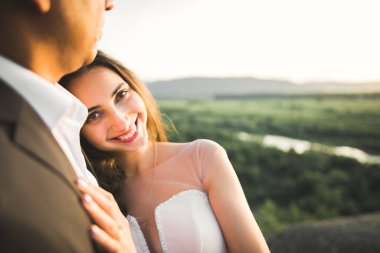 Doğadaki düğün çifti birbirine sarılıyor. Beyaz elbiseli güzel bir kız. Takım elbiseli adam.