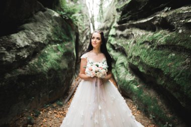 Çekici gelinin portresi, uzun saçlı, büyük buketli poz veren..