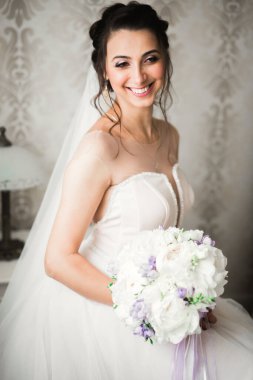 Beyaz elbiseli lüks gelin düğün törenine hazırlanırken poz veriyor..