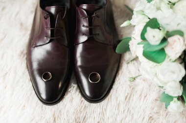 İki altın alyanslı erkek ayakkabıları ve farklı çiçekli güzel bir düğün buketi, güller..