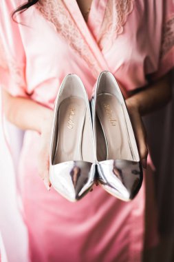 Zarif beyaz elbiseli güzel gelin ellerinde düğün ayakkabıları tutuyor..