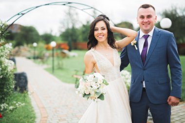 Güzel, genç bir çift ellerinde çiçeklerle poz veriyorlar..