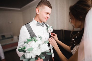 Gelin, damat ceketine yeşil yapraklı beyaz yaka çiçeğini iğneledi..