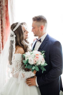 Romantik düğün anı, yeni evli çiftin gülümseyen portresi, gelin ve damadın kucaklaşması.