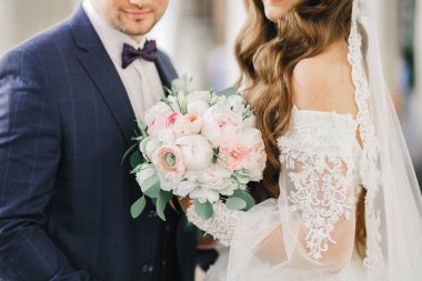 Güzel, genç bir çift ellerinde çiçeklerle poz veriyorlar..