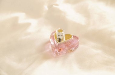 Beyaz bir bez yüzeyde kalp şeklinde parfüm şişesi..