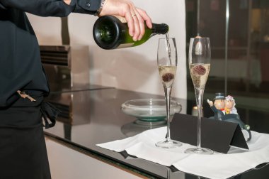 Bir garsonun servis ettiği ekşi kirazlı iki bardak şampanya..