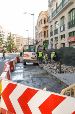 Works on a sidewalk in the city center due to a broken water pipe diverting traffic from the road.