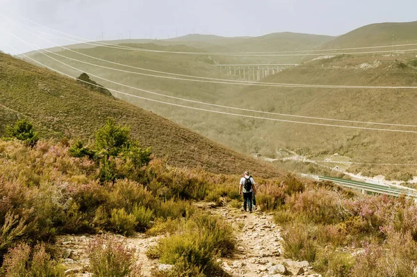 Two hikers walk down a slope during a hot day in the Tejedelo area, Zamora, Spain.