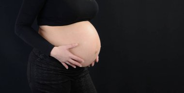 Pregnant woman with hands on her belly. Body part.