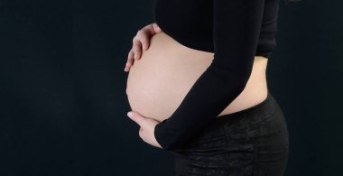 Pregnant woman in an advanced state of pregnancy with her hands on her belly.